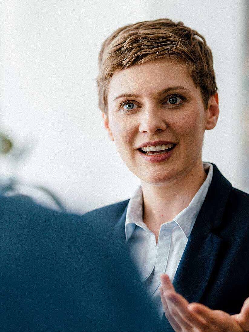 Frau mit kurzen Haaren und Businessanziehsachen spricht 